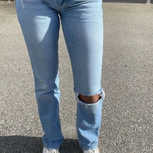 Ljusa jeans med slitning - Säljer ett par ljusa jeans med slitning på knät. De har en bootcut passform och är perfekta bas plagg för t.ex. Stockholm stil. Jeansen är i bra skick och passar till både vardag och fest.💕