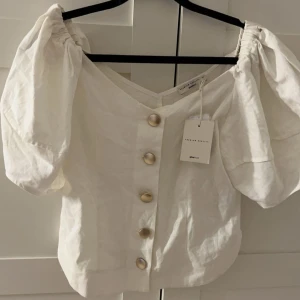 Vit blus från Gina Tricot - Säljer en superfin vit blus från Gina Tricot i bra skick. Den har puffiga kortärmar och knappar framtill. Perfekt för både vardag och fest💞