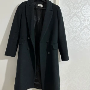  kappa från MNG - Säljer en elegant kappa från MNG i storlek XS. Den har en klassisk design med knappar framtill och långa ärmar. Perfekt för höst och vinter, och ger en stilren look till vilken outfit som helst. Kappan är i mycket bra skick och redo för nya äventyr!