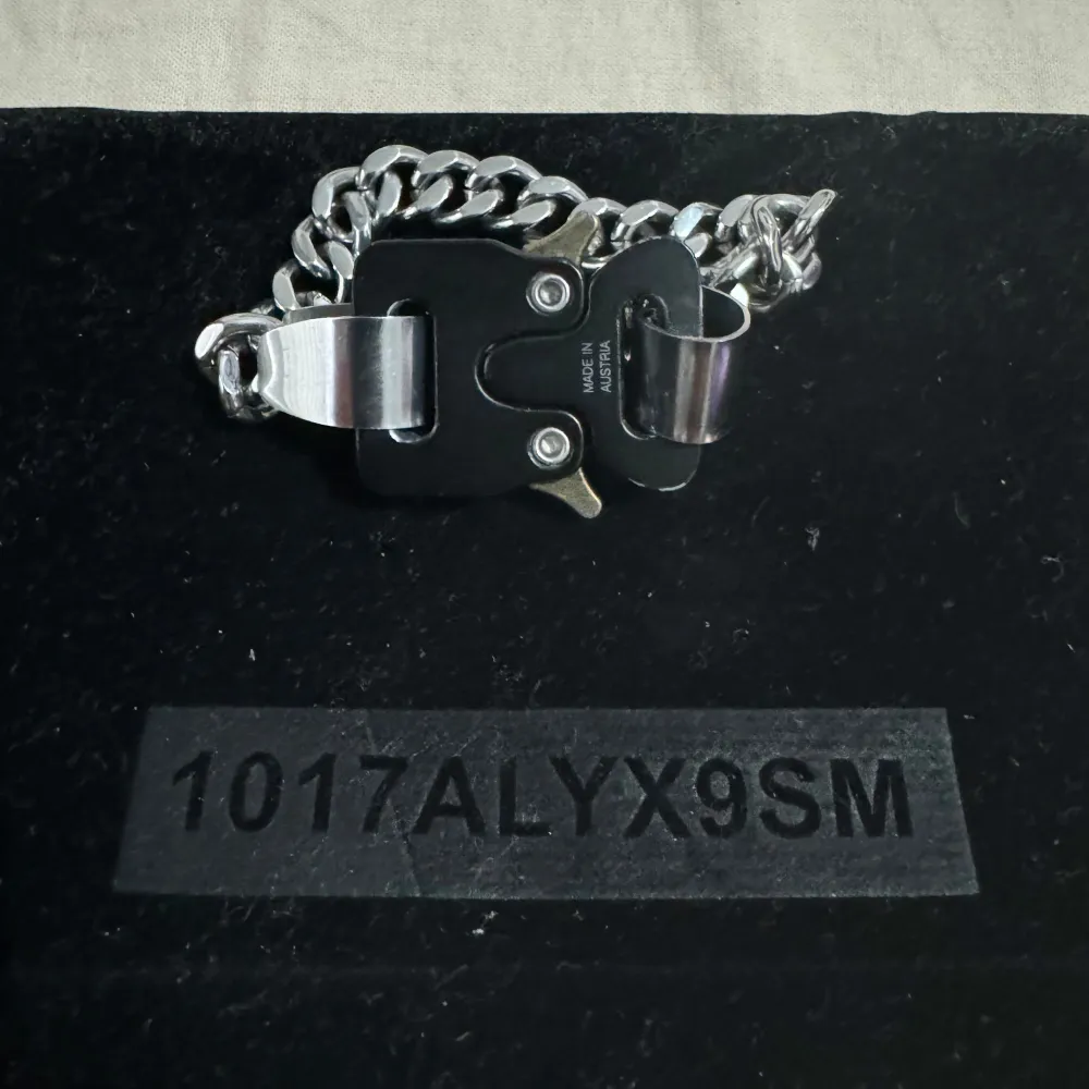 Säljer ett stilrent och modernt armband från 1017 ALYX 9SM. Armbandet är silverfärgat med en robust kedja och en unik svart spänndetalj. Perfekt för att ge din outfit en edgy touch. Kommer med originalförpackning.. Accessoarer.