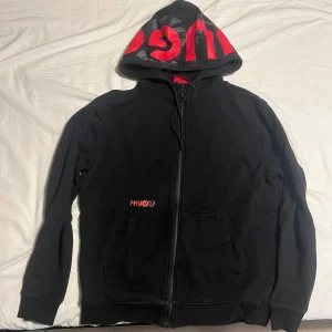 Hugo hoodie - Säljer en snygg svart hoodie från Hugo Boss som är väldigt sällsynt och inte går att få tag på längre med röd logga på huvan. Bra skick. Perfekt för höst och vår.. Storleken är S, men skulle lika gärna kunna passa någon i M. Tveka inte på att ställa frågor, byten kan funka