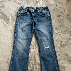 Blå jeans med slitningar - Säljer ett par blå jeans i ny skick med coola slitningar på framsidan. De har inga defekter och är i storlek s/m Midjemåttet är 40cm, innerbenslängd är runt 75 cm och grenmåttet är 15 cm💞