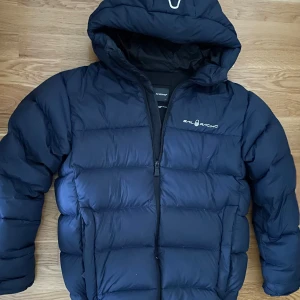 Mörkblå pufferjacka - Sail Racing - JR CLOUD DOWN HOOD! Jackan är helt ny alldrig använd nypris ligger på 2499kr Perfekt Snygg och Varm Vinterjacka i storlek 176cm (Pris Kan Diskuteras vid Väldigt snabb äfär) 