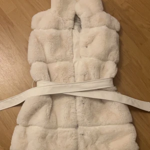 Vit pälsväst från Amisu - Säljer en supermjuk och fluffig vit pälsväst från Amisu i storlek 34. Västen har ett bälte i midjan för en snygg passform och är perfekt för kyliga dagar. Den är i mycket bra skick och redo för nya äventyr. Passar perfekt till både vardag och fest! 🤍pris kan diskuteras,