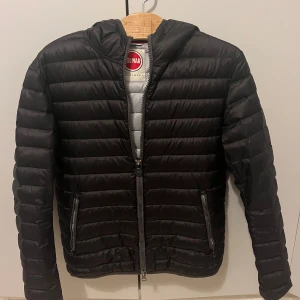  Colmar jacka - Säljer en snygg svart pufferjacka från Colmar i storlek 50. Jackan har en dragkedja framtill och är perfekt för höst och vinter. Den är i mycket bra skick och har en stilren design med Colmar-loggan på ärmen. Perfekt för att hålla värmen när det är kallt ute! Inga defekter på den!