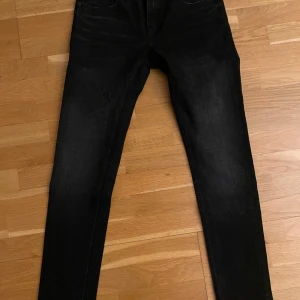 Svarta jeans från Crocker - Säljer ett par svarta jeans från Crocker i bra skick. De har en klassisk femficksdesign och är perfekta för både vardag och fest. Jeansen är i en mörk svart färg och har en snygg passform. Perfekta för höst och vinter! Storlek 29/32