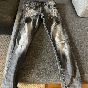 Grå jeans från Supply & Demand - Säljer ett par grå jeans från Supply & Demand i storlek XS. De har en cool slitningseffekt och en tight passform. Perfekta för en avslappnad stil med lite edge. Använda men i bra skick. Passar perfekt till både vardag och fest!