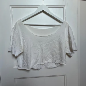 Vit croppad topp - Säljer en enkel och stilren vit croppad topp. Den är kortärmad och har en lös passform, perfekt för sommardagar. Toppen är i bomull och känns skön mot huden. Passar bra till både jeans och kjol för en avslappnad look.