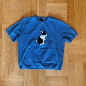 Stickad Blå tröja med kaninmotiv - Blå stickad kortärmad i storlek S. Tröjan är i gott begagnat skick och är enbart använd fåtal gånger. Klicka gärna på köp nu och meddela för eventuella frågor. :)