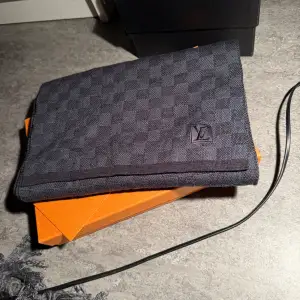 Säljer en elegant grå halsduk från Louis Vuitton i ett klassiskt rutmönster. Den är i nytt skick och kommer i sin originalförpackning. Perfekt för vintern och ger en lyxig touch till vilken outfit som helst. Passa på att köpa denna stilrena accessoar!