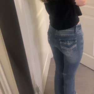 Blå jeans med broderade detaljer - Säljer ett par snygga blå jeans med broderade detaljer på bakfickorna. De har en klassisk femficksdesign och en bekväm passform. Perfekta för både vardag och fest! 🦋