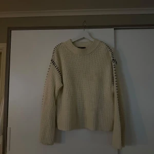 Stickad tröja med detaljer  - En creme vit stickad tröja med svarta detaljer på ärmen.  Använd ett fåtal gånger!