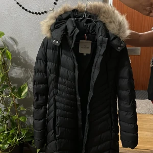 Svart dunjacka från Moncler - Säljer en snygg svart dunjacka från Moncler med pälskantad huva. Perfekt för kalla vinterdagar. Jackan har en figursydd passform och stängs med dragkedja. Den är i mycket bra skick! 🙏🏼 för mer information nås jag via dm på plick.  (Ej äkta)
