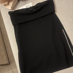 Svart topp med dragkedja - Snygg svart topp i normal passform med en cool dragkedjedetalj på sidan. Helt oanvänd och prislappen finns fortfarande kvar. Ordinarie pris 329