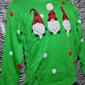 Grön jultröja med tomtar - Supermysig grön jultröja med tre söta tomtar på framsidan. Tröjan har långa ärmar och är dekorerad med vita och röda prickar. Perfekt för julfirandet och att hålla sig varm under vintern. 🎅🎄