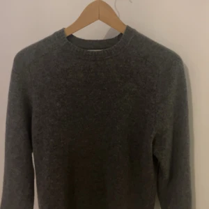 Grå Kashmir tröja från Zara - Säljer en stilren grå tröja från Zara i storlek M. Den är i mycket bra skick och perfekt för både höst och vinter. Tröjan är långärmad och har en normal passform med ribbade muddar vid ärmslut och nederkant. Supermjuk och bekväm!