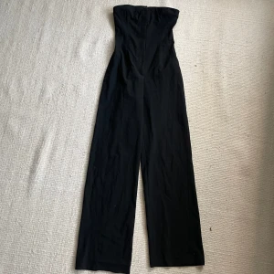Figursydd Jumpsuit - Figursydd svart jumpsuit från Pull&Bear. Storlek S. Bandeau med knapp samt sydda sömmar i midjan. Kostym stil samt med raka långa ben. Sitter perfekt på mig som vanligtvis har XS/S i storlek.