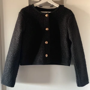 Svart boucléjacka med guldknappar🖤 - Säljer en elegant svart boucléjacka med fina guldknappar framtill. Jackan är croppad och har en klassisk rund halsringning. Perfekt för höst och vår, och funkar både till vardags och fest. Den är långärmad och ger en stilren look.🖤
