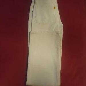 Vita jeansbyxor - Säljer ett par vita jeansbyxor i bra skick. De har en klassisk femficksdesign och är perfekta för både vardag och fest. Byxorna har en normal passform och är tillverkade i ett slitstarkt material. Perfekta för vår och sommar!