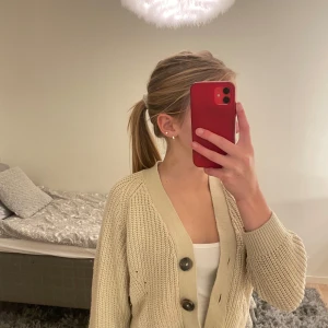 Beige stickad kofta - Säljer en superfin beige stickad kofta med stora knappar framtill. Perfekt för höst och vår, den är både mysig och stilren. Koftan har en normal passform och är i mycket bra skick. Passar perfekt till både jeans och kjol!