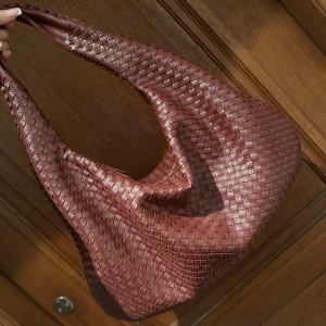 Burgundy flätad väska - Säljer den populära väskan i burgundy/mörkröd färg med flätat mönster. Fått så mycket komplimanger när jag gått med väskan på stan!❤️Väskan har en stilren design, vilket gör den lätt att matcha med olika outfits. Det är den större modellen så man får också plats med dator!! Inköpt på en webbshop i somras för 700kr