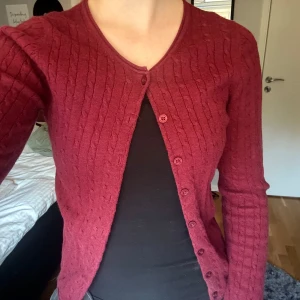 Vinröd kofta från Boomerang - Säljer en superfin vinröd kofta från Boomerang i väldigt bra kvalitet. Den är kabelstickad och i 100% ekologisk bomull. 