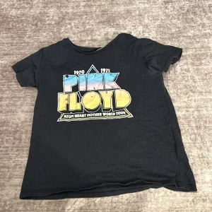 Svart Pink Floyd t-shirt från H&M - Säljer en svart Pink Floyd t-shirt från H&M med färgglatt tryck på framsidan och turnélista på baksidan. Perfekt för musikälskare! T-shirten är i bra skick och har korta ärmar. Jag säljer den för att den är för liten 