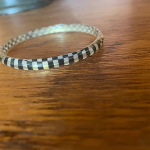 Svartvitt rutigt armband - Snyggt och stilrent armband med ett svartvitt rutigt mönster. Perfekt för att ge en cool touch till din outfit. Armbandet är i bra skick och passar till både vardag och fest. Ett måste för den som gillar unika accessoarer!