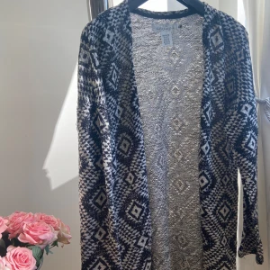 Svartvit mönstrad kofta - Säljer en snygg svartvit kofta med geometriskt mönster. Perfekt för höst och vinter, den är långärmad och har en skön passform. Koftan är i mycket bra skick och passar både till vardags och lite finare tillfällen. Ett måste i garderoben för den som gillar stilrena plagg!