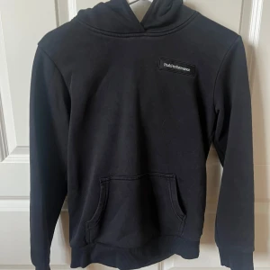 Svart hoodie från Peak Performance - Säljer en svart hoodie från Peak Performance i bra skick. Den har en klassisk design med en känguruficka fram och en bekväm huva. Perfekt för både vardag och träning. Passar till allt och är supermysig att ha på sig!