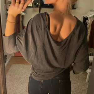 Grå omlottopp från Filippa K - Säljer en snygg grå omlottopp från Filippa K i storlek XS. Toppen har en avslappnad passform med trekvartsärmar och en stilren design. Perfekt för både vardag och fest! 💫