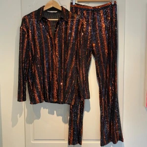 Paljett-sett Zara - Supercoolt paljett-sett med skjorta och byxor från Zara. I svart och orange. Skjorta i M och byxor XS. Använt 2 gånger, mycket fint skick!