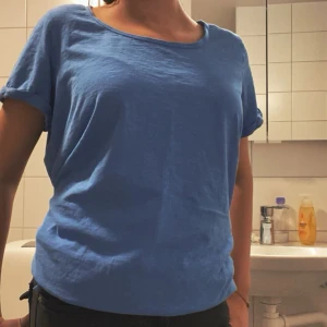 En blå kortärmad tröja med en bred nacköpning  - Tröjan är i storleken L och har inte anan använt mer än 3-4 gånger det är som en t-shirt men har stretch material längst ner i tröja. 