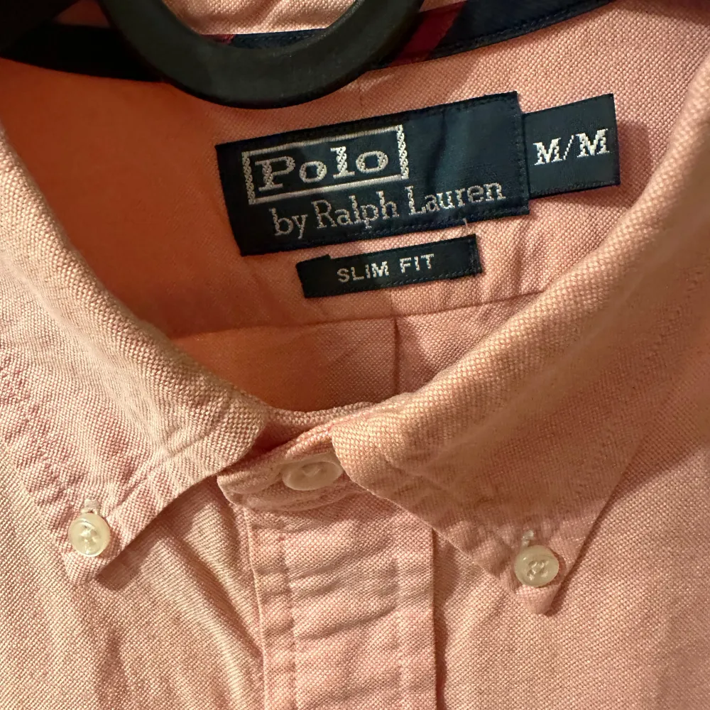 Säljer en snygg rosa skjorta från Polo Ralph Lauren i storlek M. Skjortan är slim fit och har långa ärmar. Den är i bomull och har klassiska knappar framtill. Perfekt för både vardag och fest!. Skjortor.