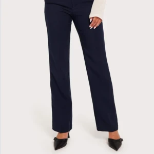 Mörkblå kostymbyxor - Säljer ett par eleganta mörkblå kostymbyxor. De har en klassisk straight passform som ger en stilren look. Perfekta för både kontoret och festligare tillfällen. Byxorna är lågmidjade/mid waist och ger en smickrande siluett.