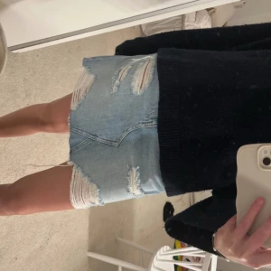 Jeanskjol - Fin blå jeanskjol men slitningar i storlek 34. Använd endast en gång men köpt här på Plick så vet inte hur många gånger innan den använts 💕  highwaist men om man har en lång tröja över syns det inte.