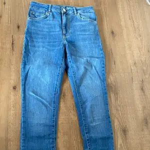 Säljer ett par snygga blå jeans från Never Denim i storlek M. De har en klassisk femficksdesign med knapp och dragkedja framtill. Jeansen är i en straight passform och är perfekta för både vardag och fest. De är i bra skick och redo för en ny ägare!