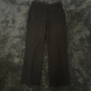 Svarta kostymbyxor från BikBok - Säljer ett par stilrena svarta kostymbyxor från BikBok i storlek 42. Byxorna har en klassisk rak passform och är perfekta för både vardag och fest. De är har en dragkedja och knapp framtill. 