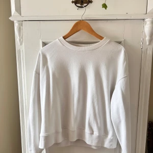 Vit sweatshirt - Säljer en stilren och enkel vit sweatshirt. Den har en normal passform med långa ärmar och ribbade muddar vid ärmslut och nederkant. Perfekt för en avslappnad look eller att mysa i hemma. Passar till alla säsonger!