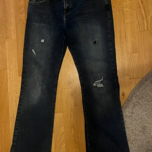 Mörkblå jeans från LTB - Säljer ett par mörkblå jeans från LTB med slitna detaljer på benen. De har en klassisk femficksdesign och en knappgylf. Perfekta för en avslappnad look!