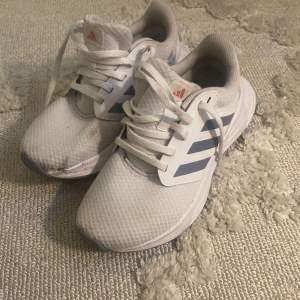 Säljer ett par vita Adidas sneakers med blå/grå ränder på sidorna. De är lite smutsiga men tvättas innan jag postar och då försvinner nog de mesta av smutsen. Perfekta för träning eller vardagsbruk!