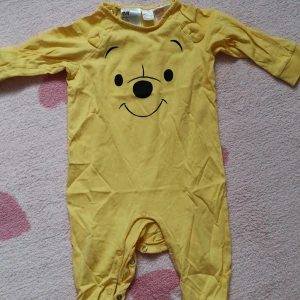 Gul babybody med Nalle Puh-motiv från H&M - Disney baby pyjamas från H&M med Nalle Puh. Storlek: 74.