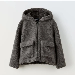 Grå teddyjacka från Zara - Mysig grå teddyjacka från Zara med huva och dragkedja framtill. Jackan har två stora fickor och är perfekt för kyliga dagar. Den är o barnstorlek 164 men passar XS-M. Håller verkligen värmen inne!✨💕
