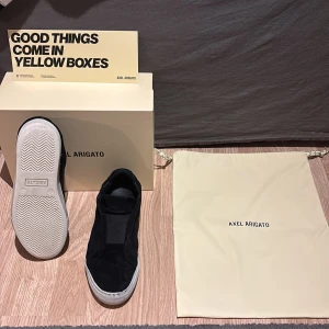 Svarta sneakers från Axel Arigato - Snygga svarta sneakers från Axel Arigato med en stilren design. Skorna har en vit sula och är tillverkade i mocka. Perfekta för en avslappnad stil.