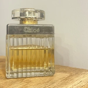 Chloé Eau de Parfum 75ml - Säljer den ikoniska Chloé parfymen med topnoter av pion, litchi och fresia ger en fräsch start, medan mellannoter av ros, liljekonvalj och magnolia tillför en blommig touch. Basnoter av virginia ceder och amber ger en varm avslutning. Flaskan är lite sliten och jag har tyvärr tappat bort rosetten🎀 Innehåller lite mer än hälften (ungefär 40ml) Nypris: 800kr