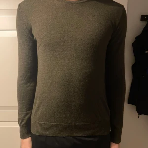 Olivgrön tröja från J.Lindeberg - Säljer en stilren olivgrön tröja från J.Lindeberg. Tröjan är långärmad och har en rund halsringning. Storlek M men passar S