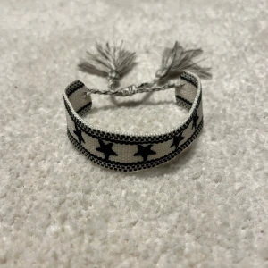 Flätat Armband  - Snyggt svartvitt armband med stjärnmönster och tofsar. Liknar det eftertraktade dior armbandet. Vid minsta fråga eller fundering hör av er🤝