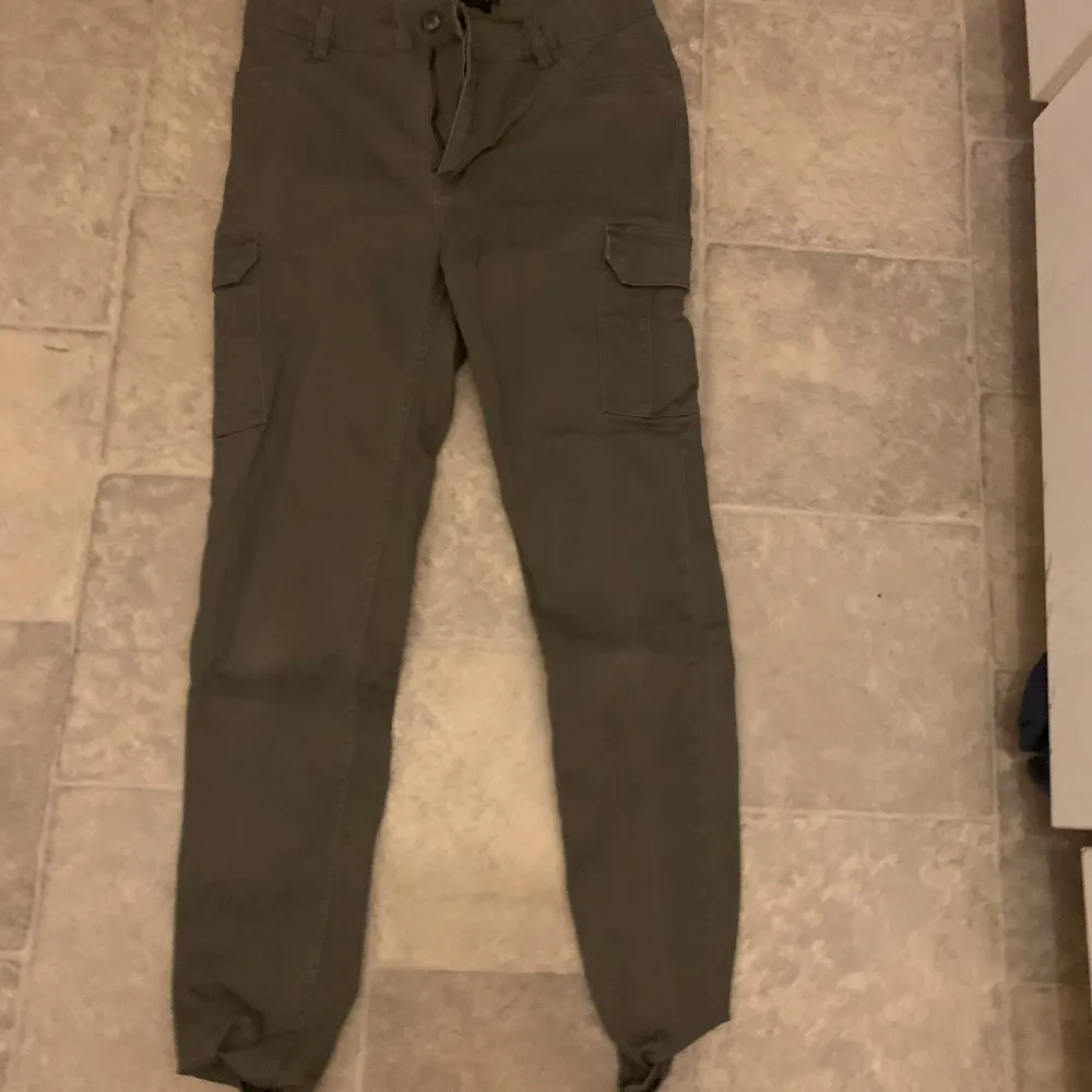 Säljer ett par gröna cargobyxor från 157. Byxorna har flera praktiska fickor och en bekväm passform med dragsko i midjan. Perfekta för en avslappnad stil.. Farkut & Housut.