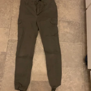 Gröna cargobyxor från 157 - Säljer ett par gröna cargobyxor från 157. Byxorna har flera praktiska fickor och en bekväm passform med dragsko i midjan. Perfekta för en avslappnad stil.