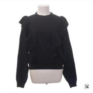 Svart tröja med volangdetaljer från & Other Stories - Snygg svart tröja från & Other Stories med volangdetaljer på axlarna och längs sidorna. Tröjan har långa ärmar och en rund halsringning, perfekt för en stilren look.